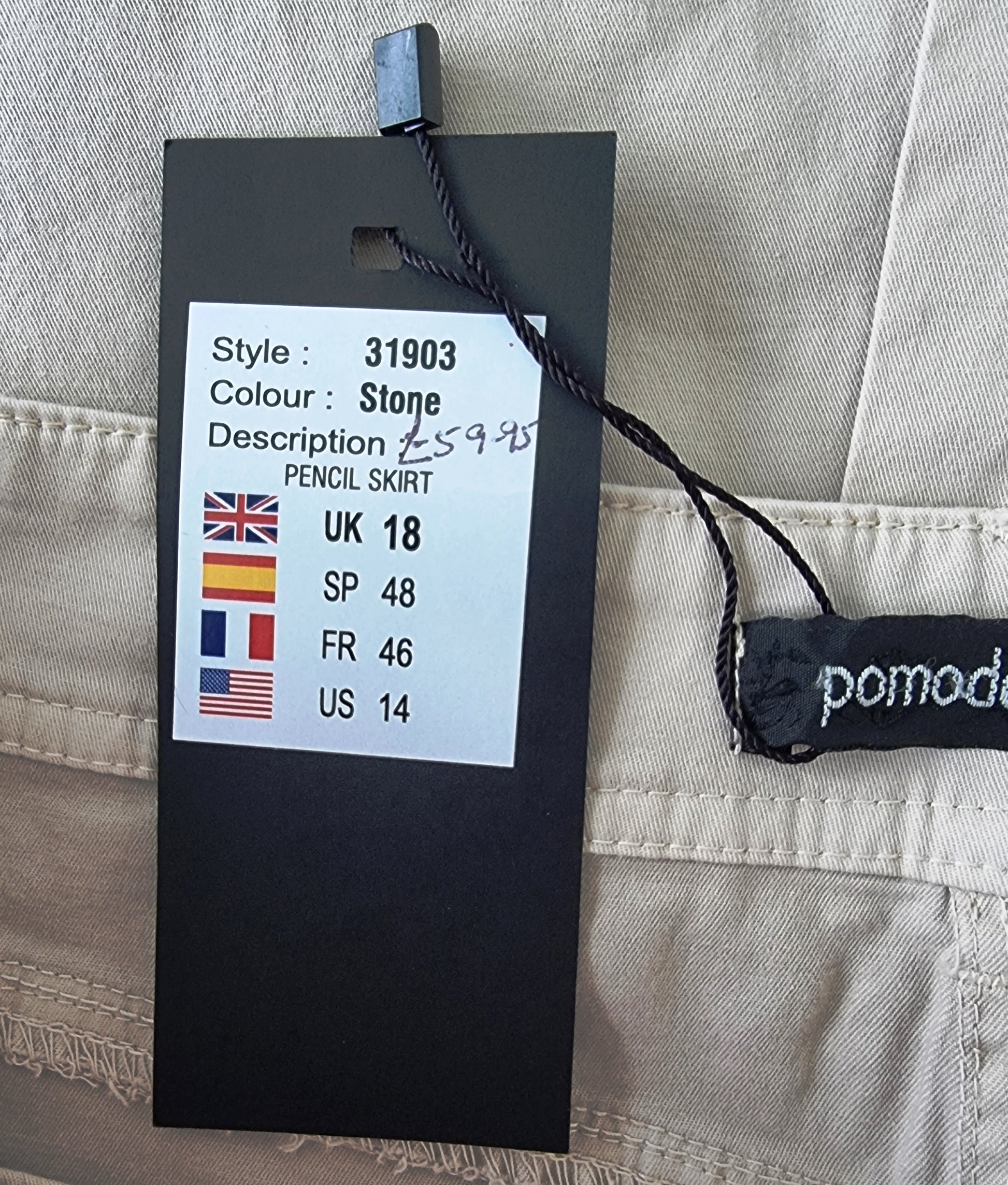 Clothing tag with size and style information on a beige fabric background