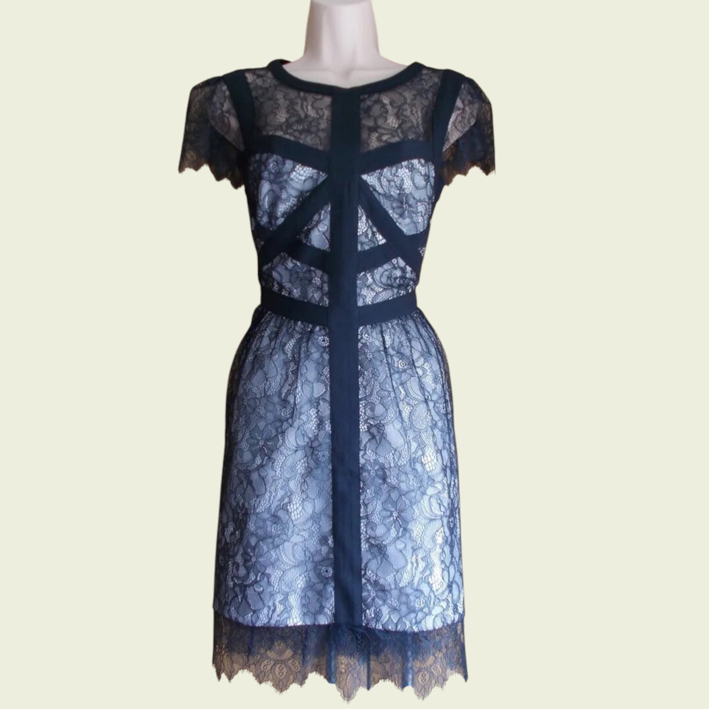 Black lace dress on a mannequin against a beige background