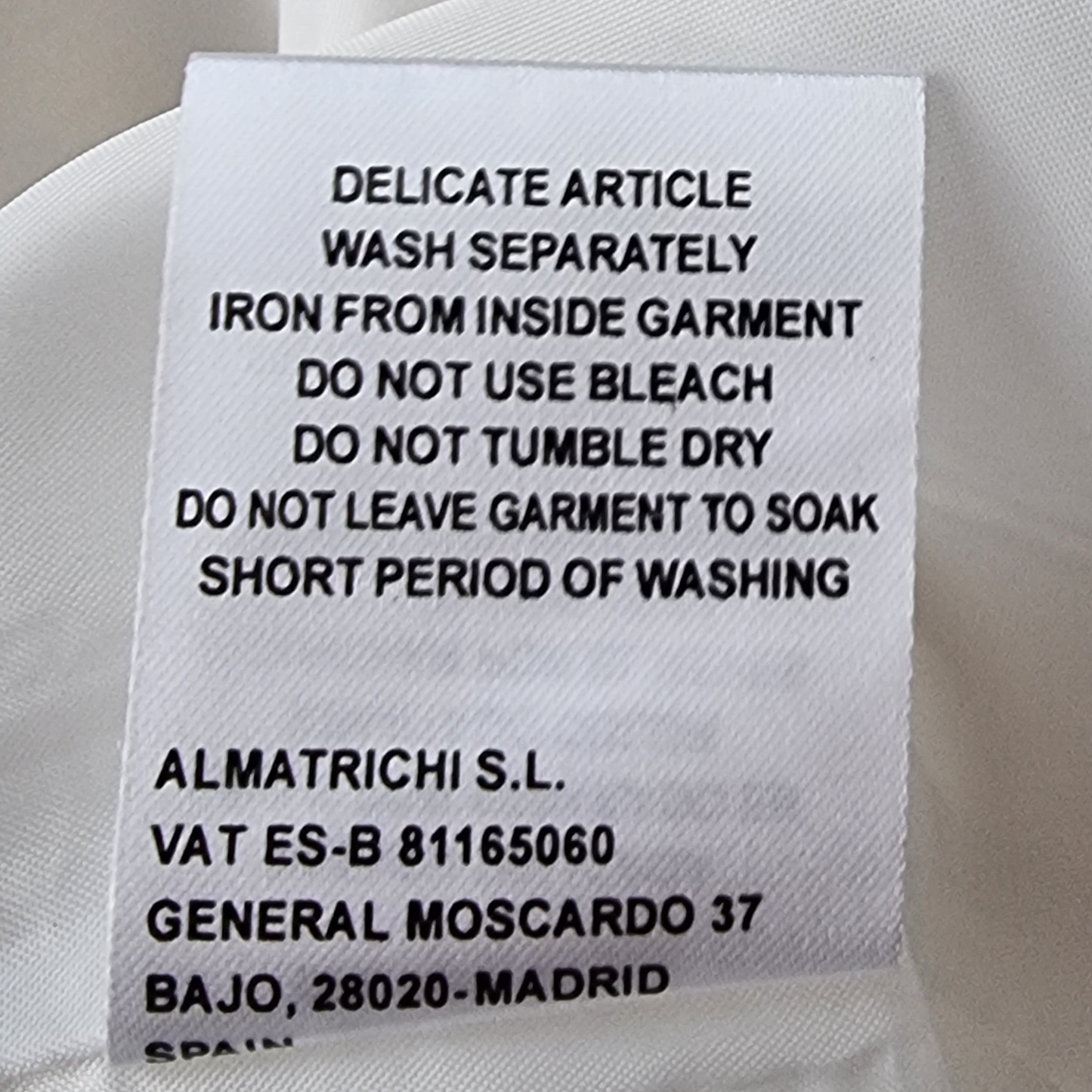 Clothing label with washing instructions and contact information on a white background