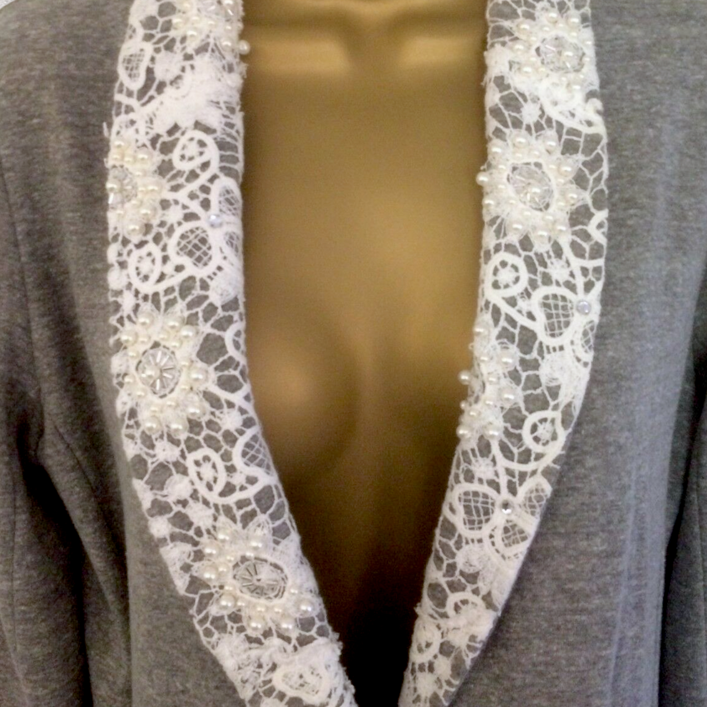 Gray jacket with white lace trim on a plain background