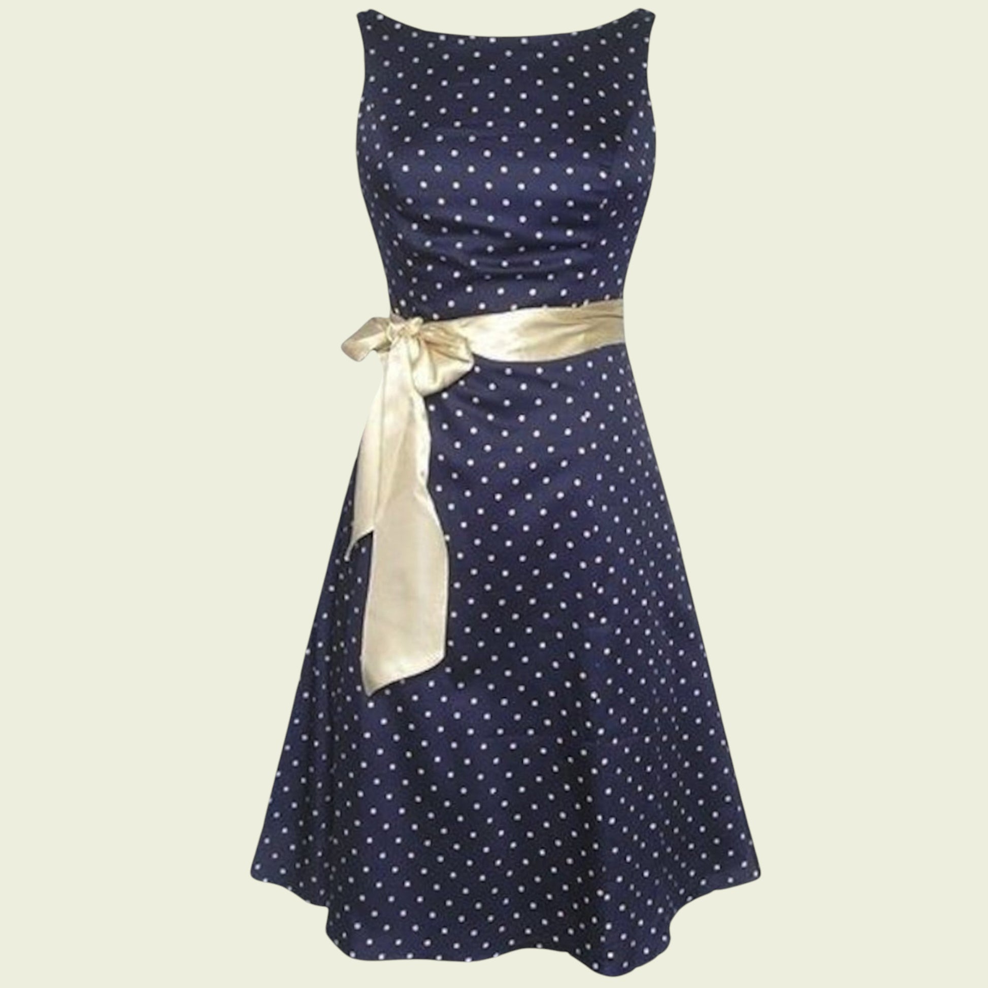Navy blue dress with white polka dots and a gold ribbon on a beige background