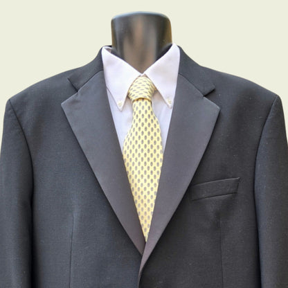 Gray suit jacket with a white shirt and yellow tie on a mannequin against a beige background