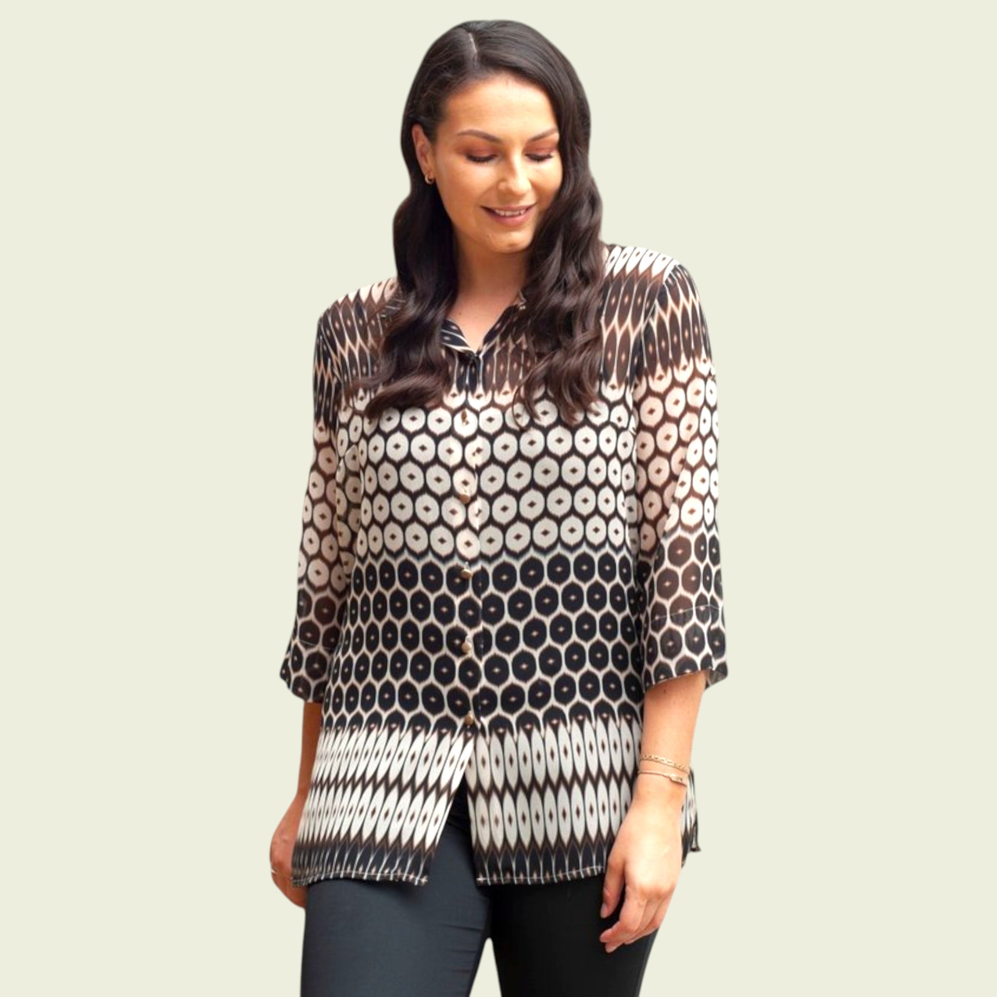 Woman wearing a patterned blouse against a plain background