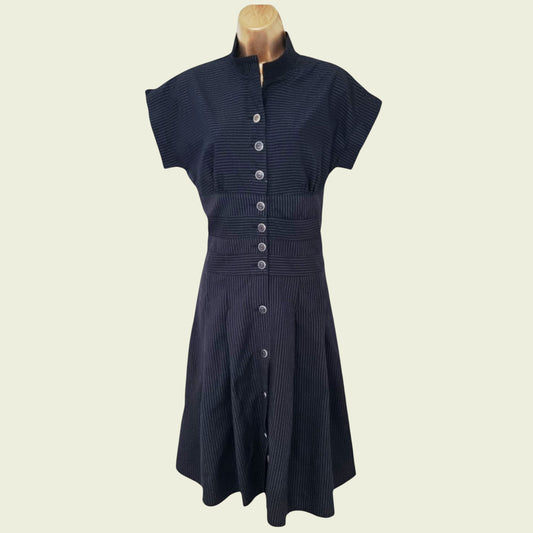 Navy dress with button details on a mannequin against a beige background