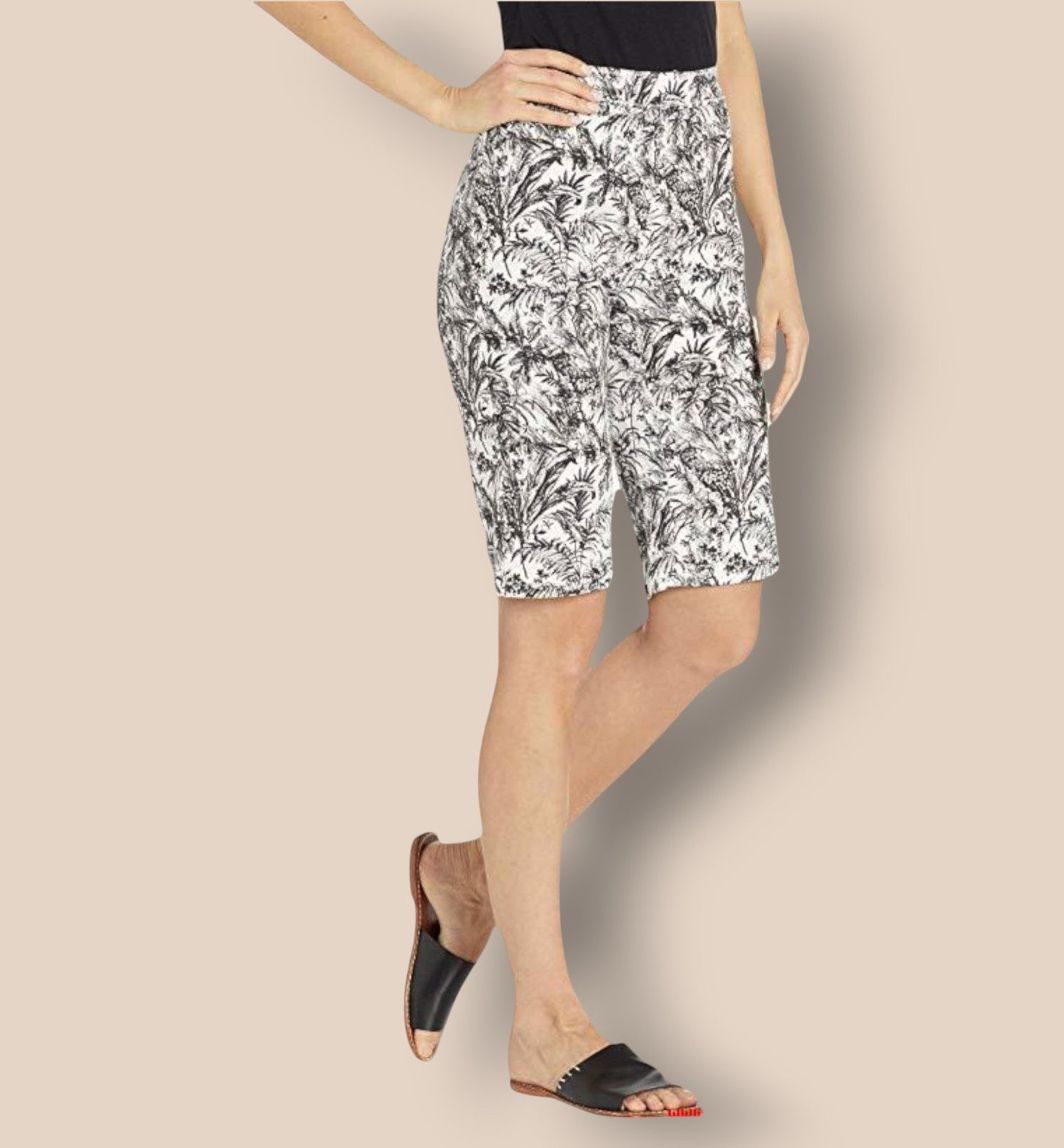 Person wearing black and white floral shorts on a beige background