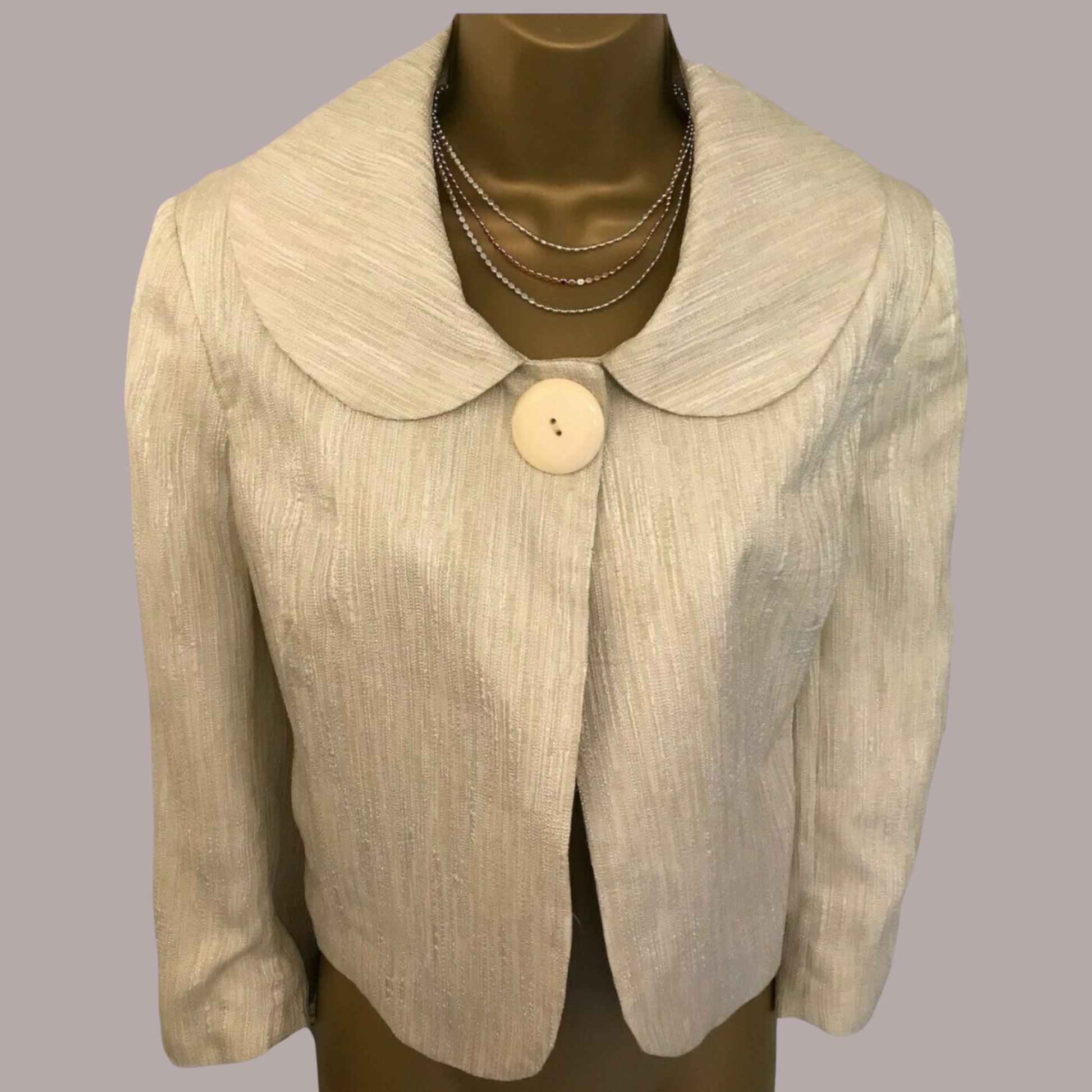 Beige blazer with a large button on a mannequin against a gray background