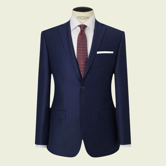 Navy blue suit jacket with a white shirt and red tie on a mannequin against a beige background