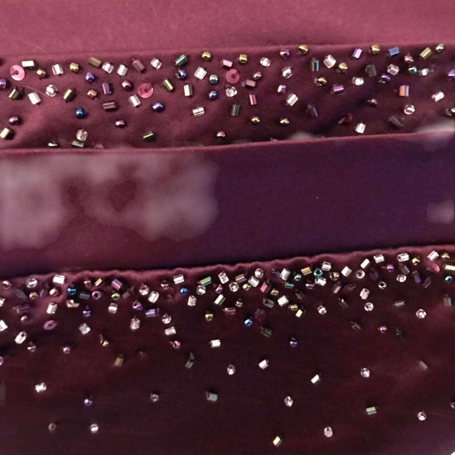 Close-up of a purple fabric with decorative beads on a pink background
