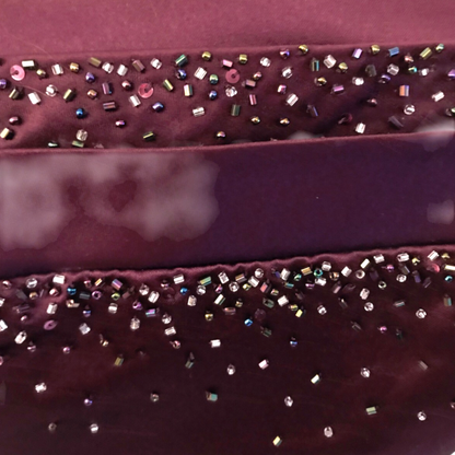 Close-up of a purple fabric with decorative beads on a pink background