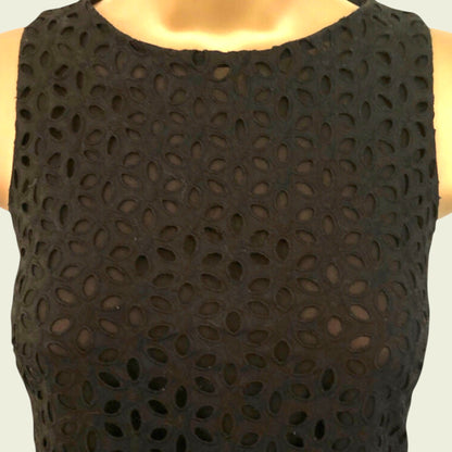Black sleeveless dress with a pattern of holes on a plain background