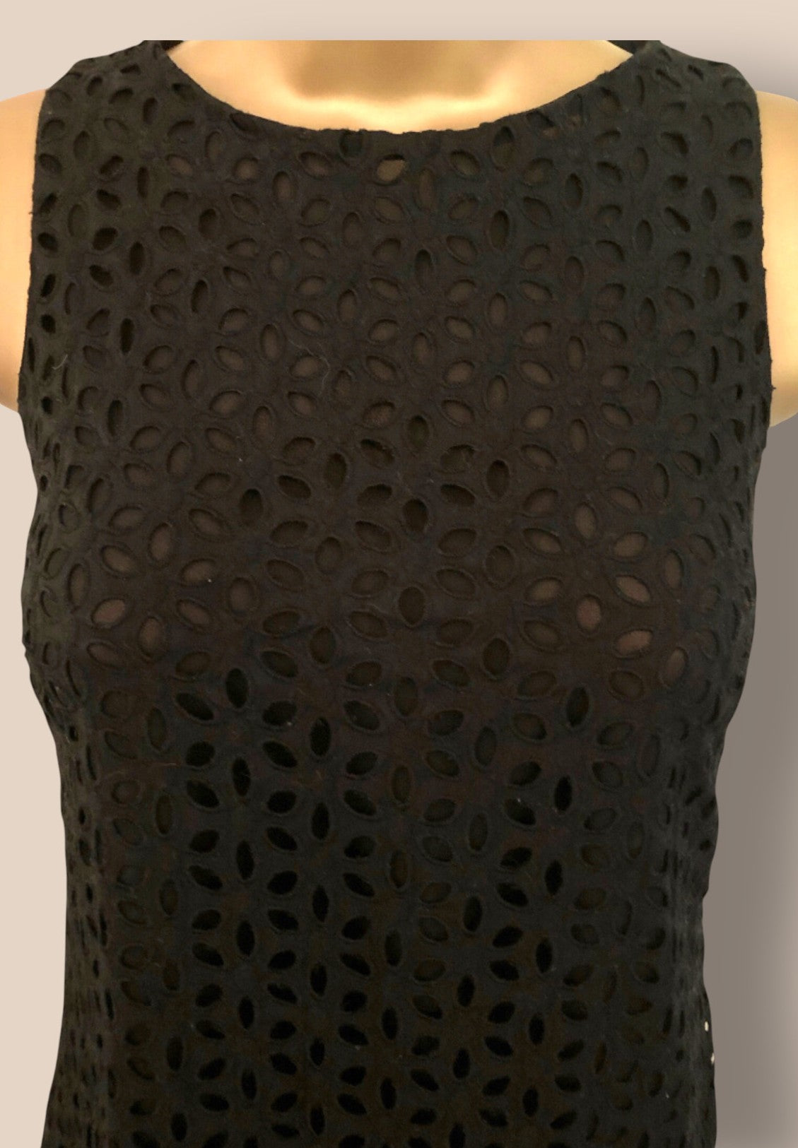 Black sleeveless top with cut-out pattern on a mannequin against a neutral background