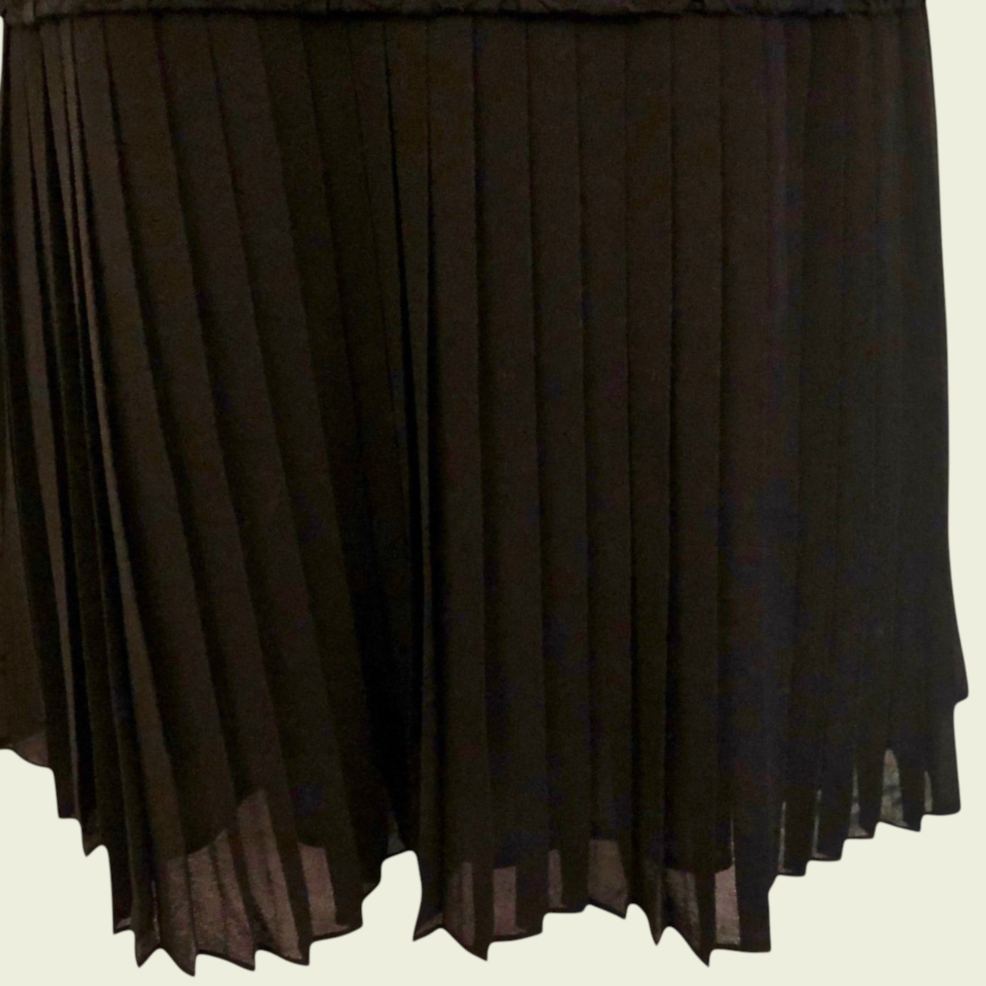 Black pleated skirt on a beige background