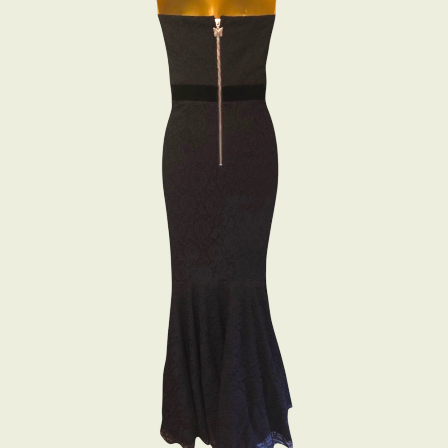 Black strapless dress with a zipper on a light green background