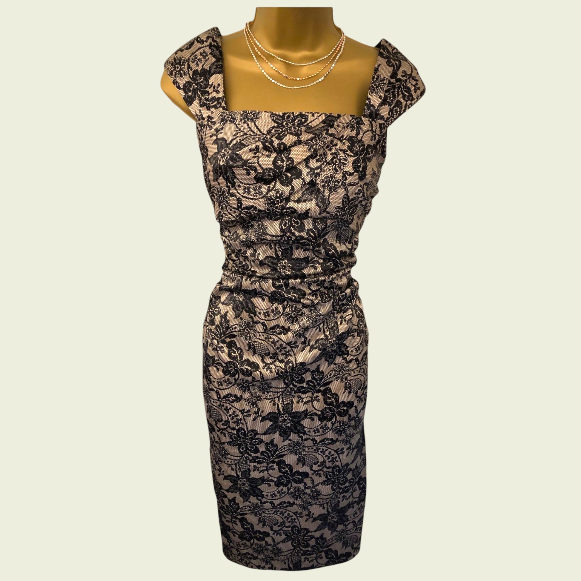 Black lace dress on a mannequin against a beige background