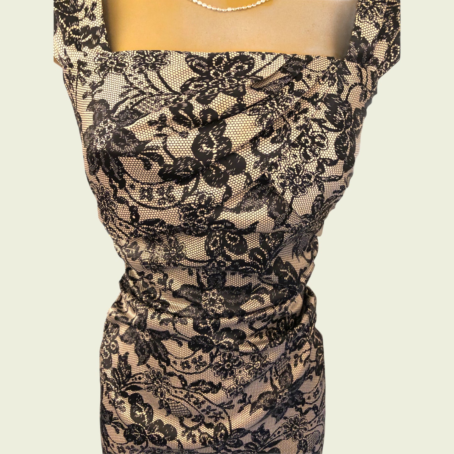 Black lace dress on a mannequin against a beige background