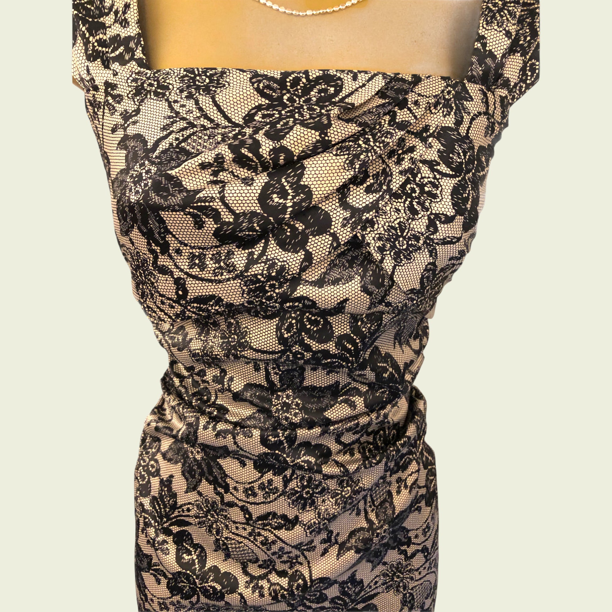 Black lace dress on a mannequin against a beige background