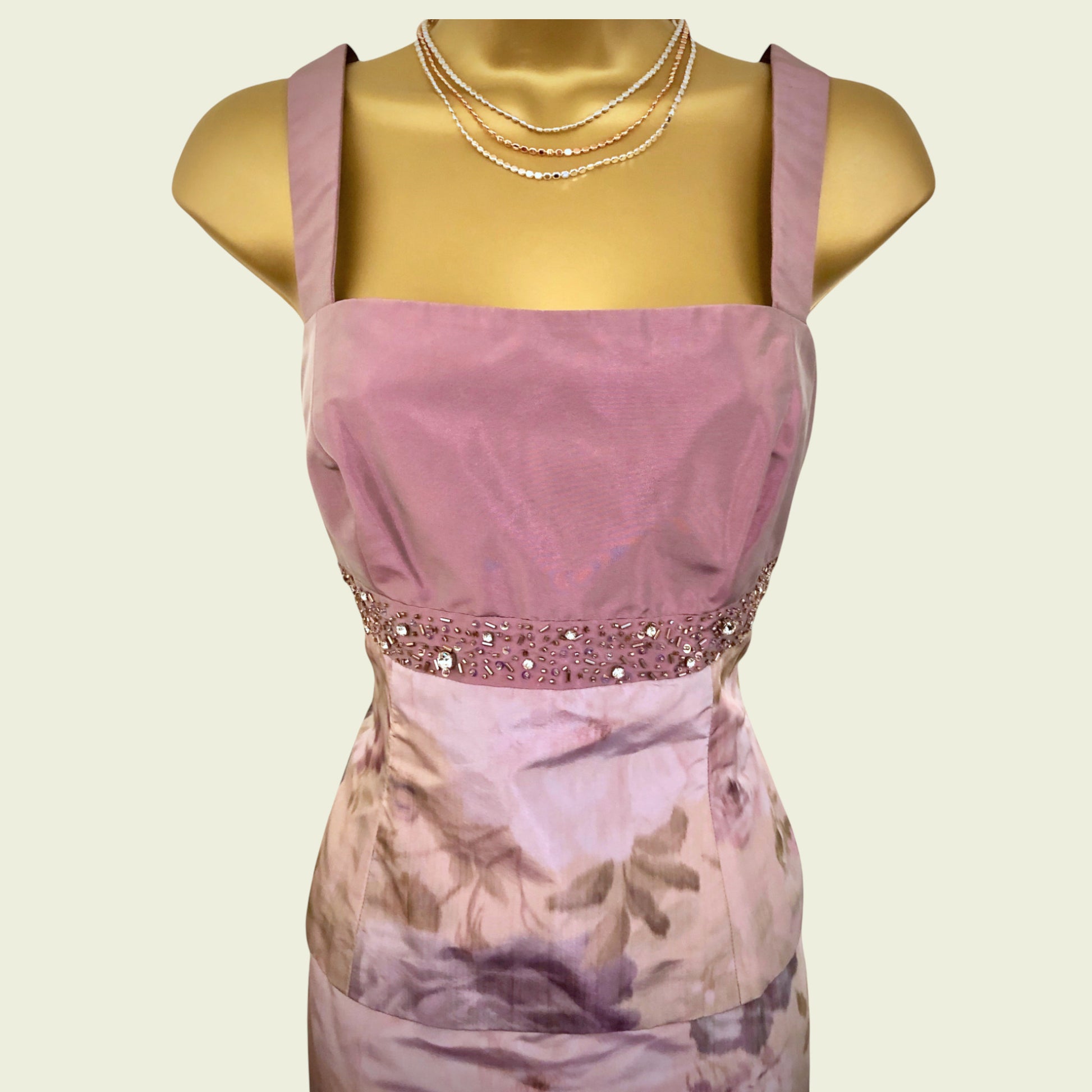 Mannequin wearing a pink dress with floral pattern on a beige background