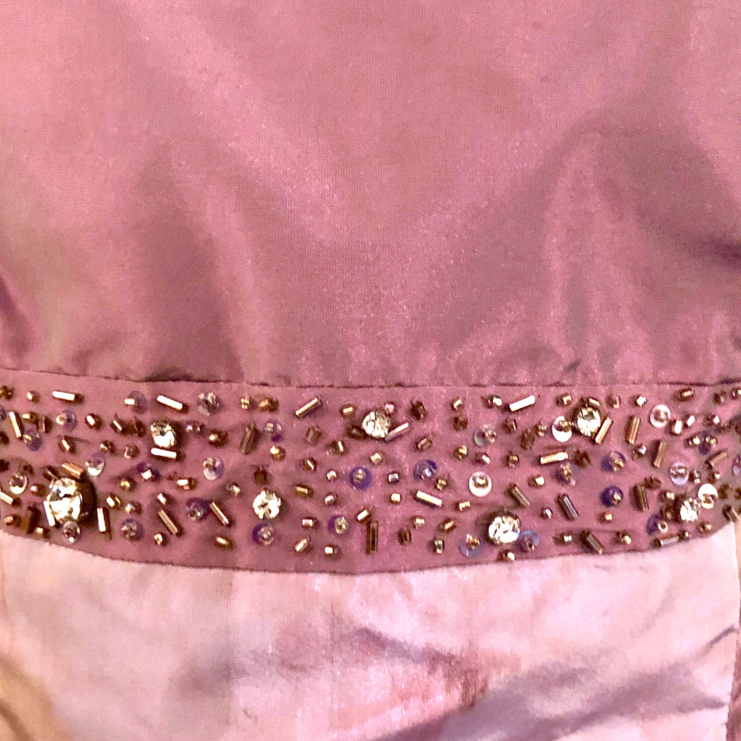 Close-up of a pink fabric with decorative beads and sequins.