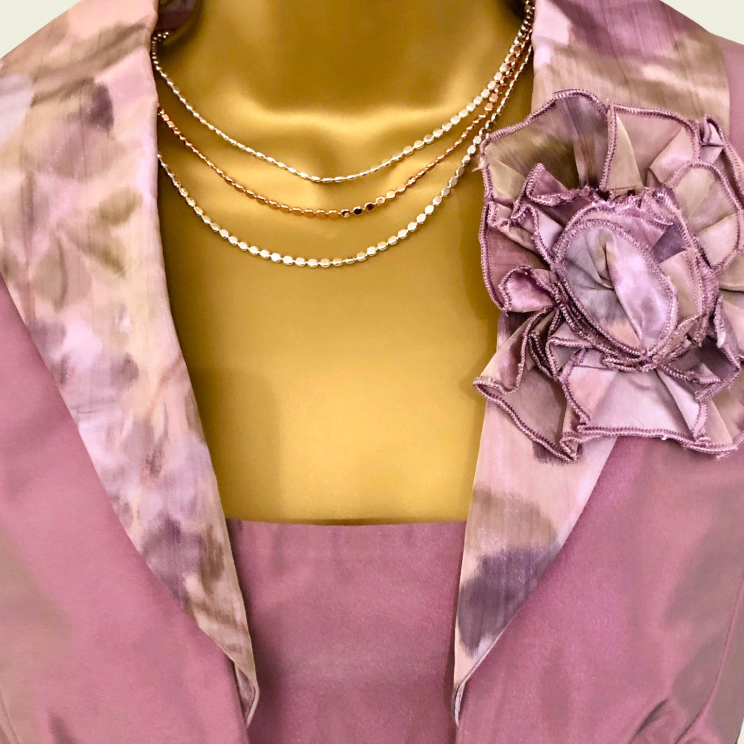 Mannequin wearing a pink floral top and gold necklace with a pink flower accessory.