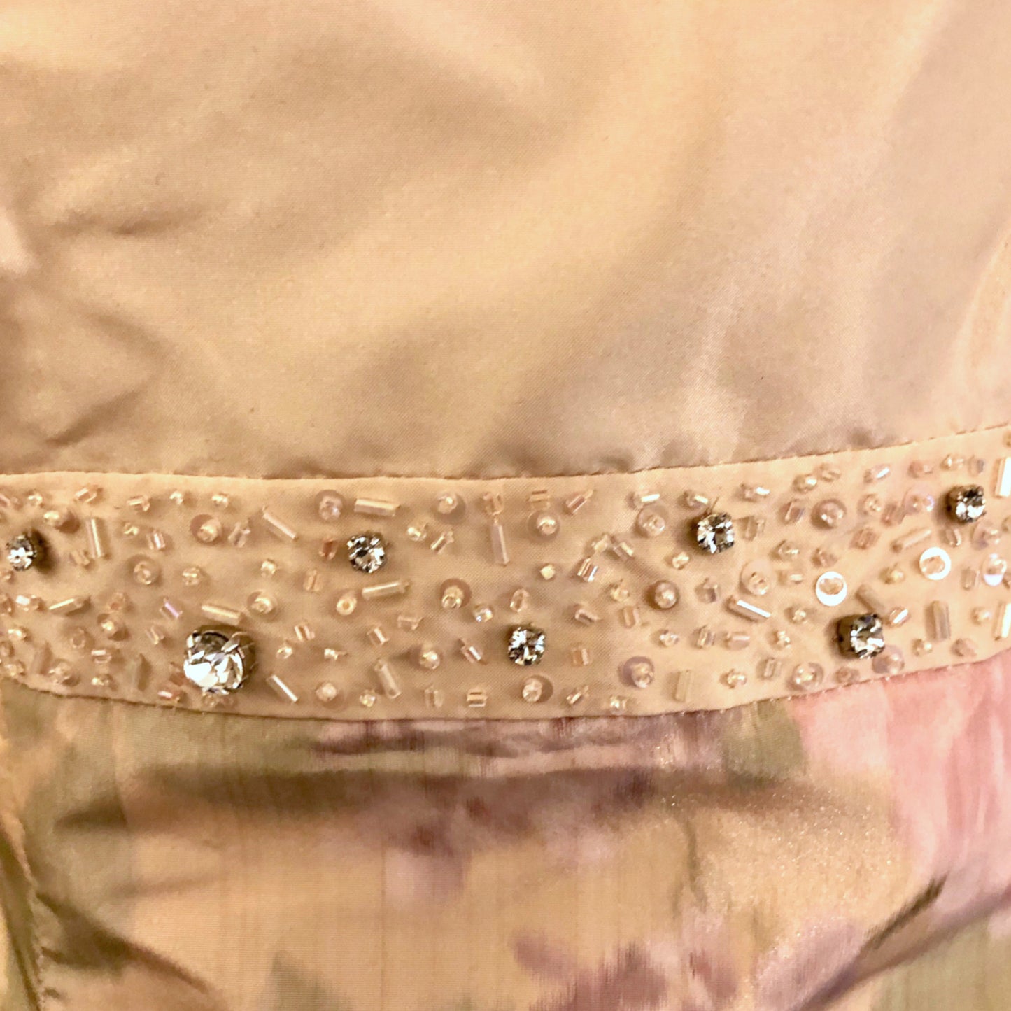 Close-up of a peach garment with decorative beads and sequins.