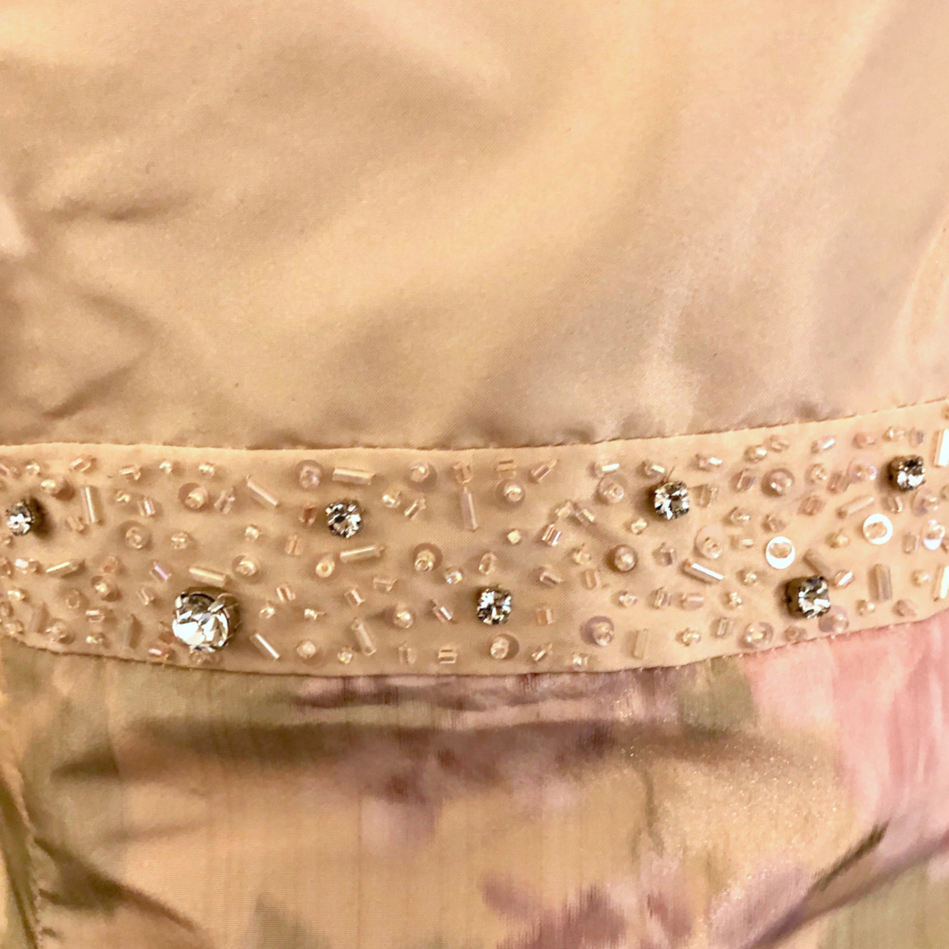 Close-up of a peach garment with decorative beads and sequins.