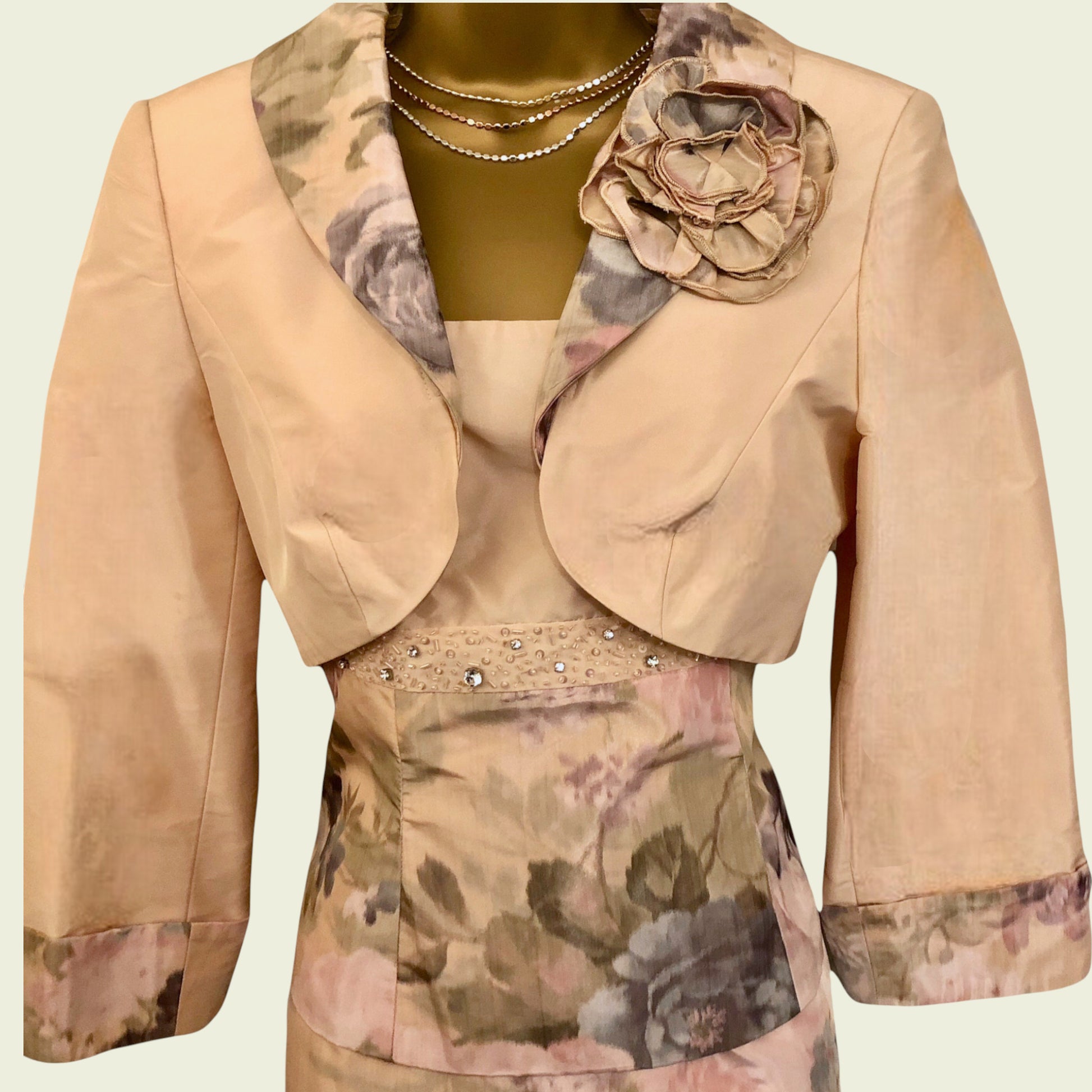Peach bolero with floral patterns and embellishments on a light green background