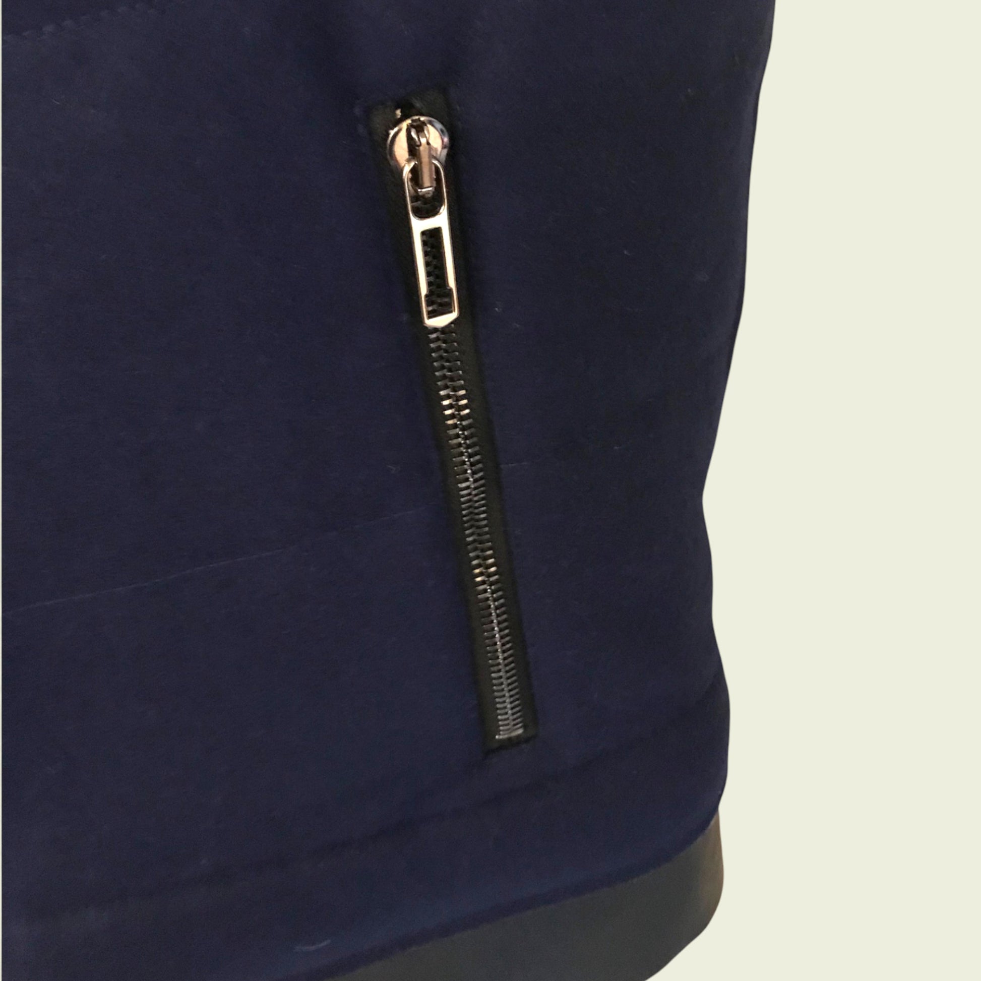 Navy blue garment with a gold zipper on a beige background
