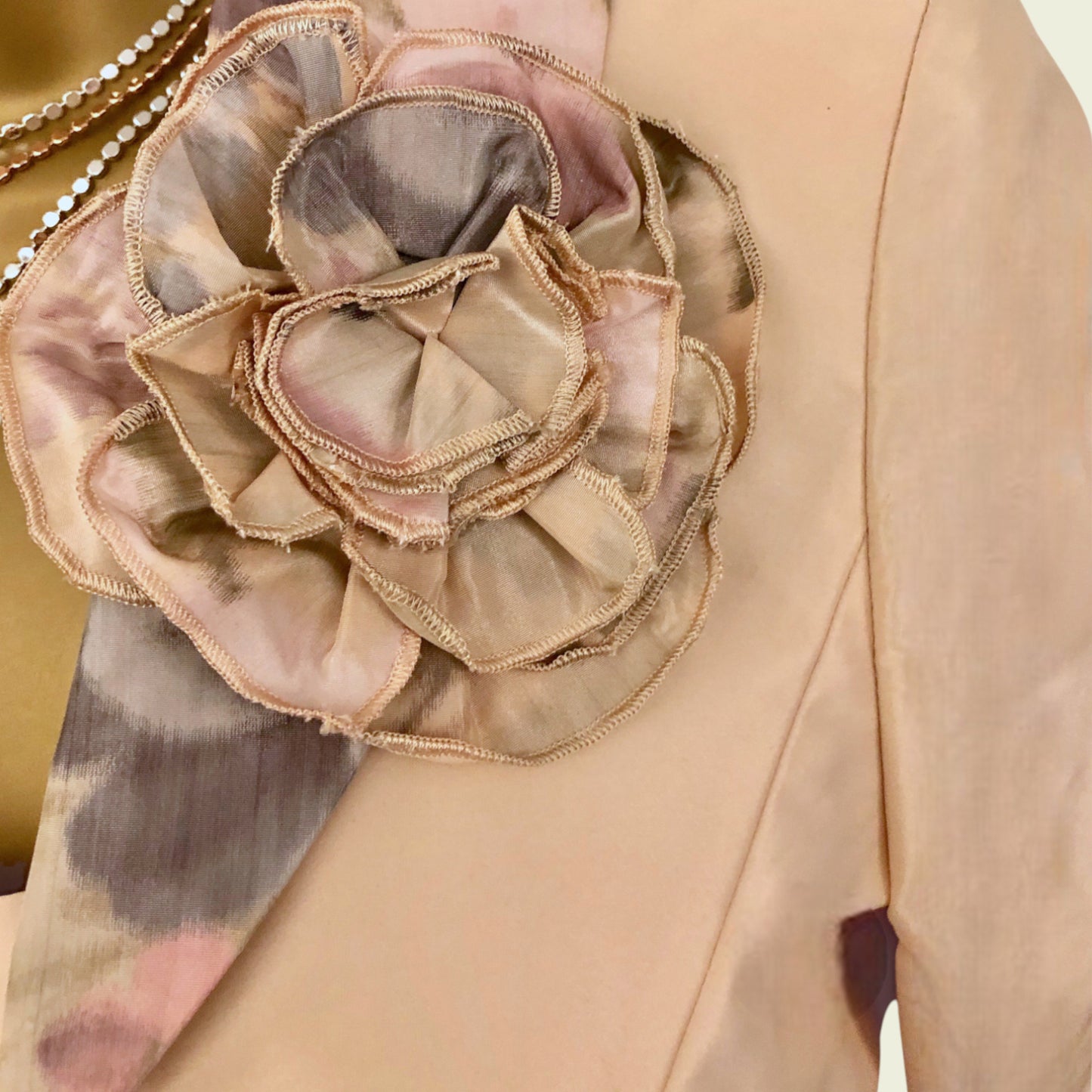 Close-up of a peach garment with a large, intricate flower embellishment.