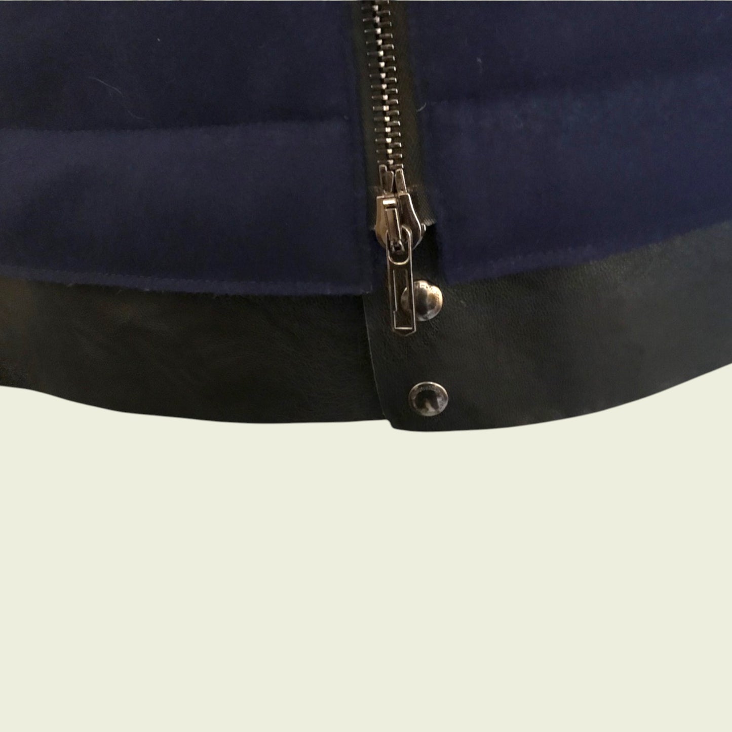 Close-up of a navy blue jacket with a zipper on a beige background