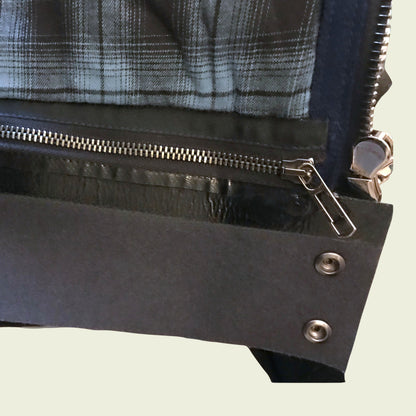 Close-up of a blue jacket with a zipper and plaid fabric inside.
