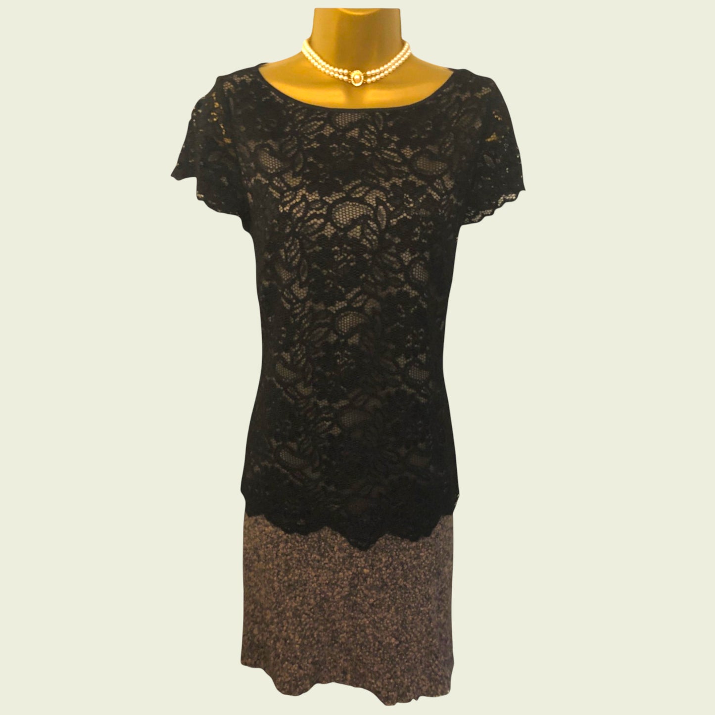 Black lace dress on a mannequin with a plain background