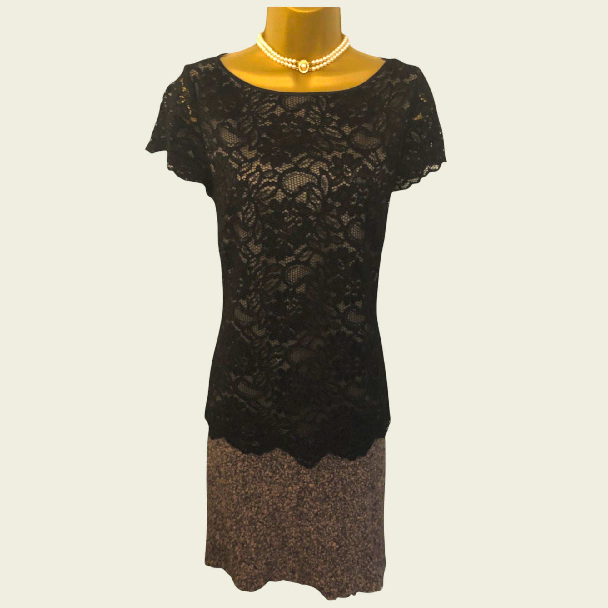Black lace dress on a mannequin with a plain background