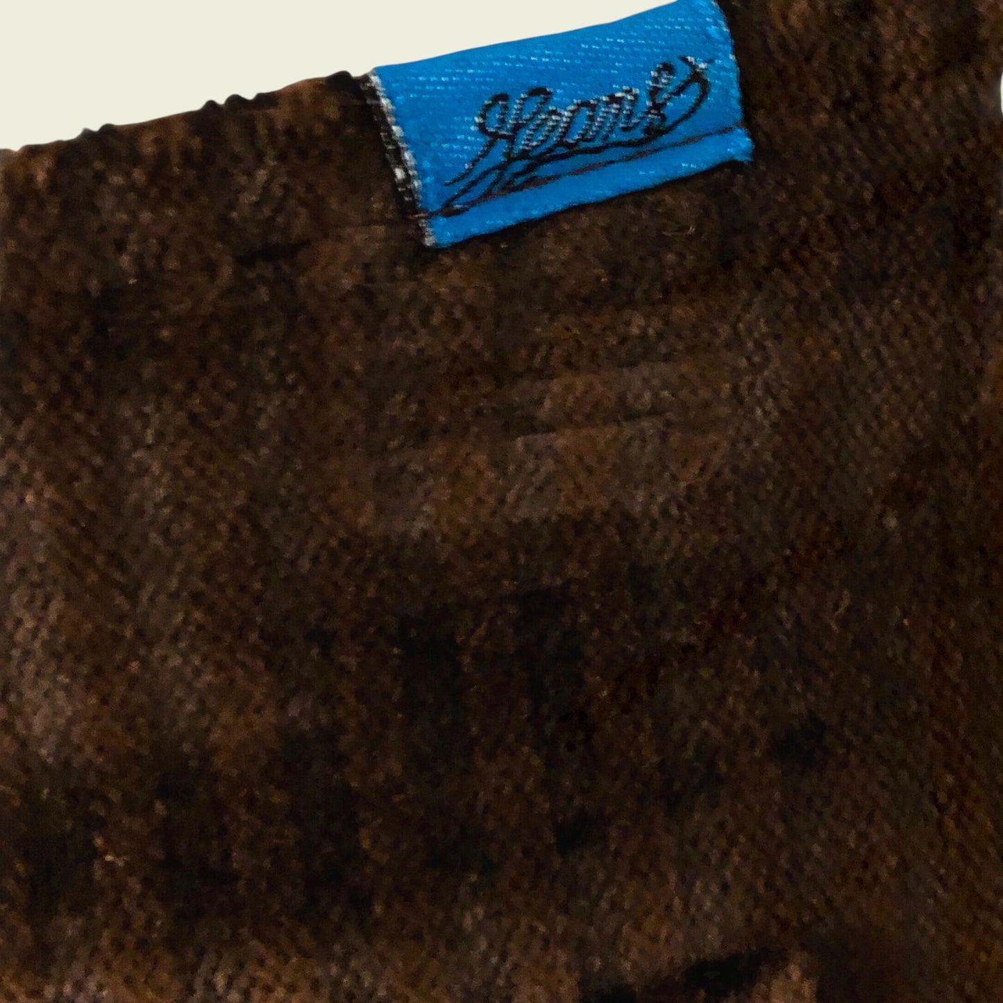 Close-up of brown fabric with a blue label featuring a logo and text.