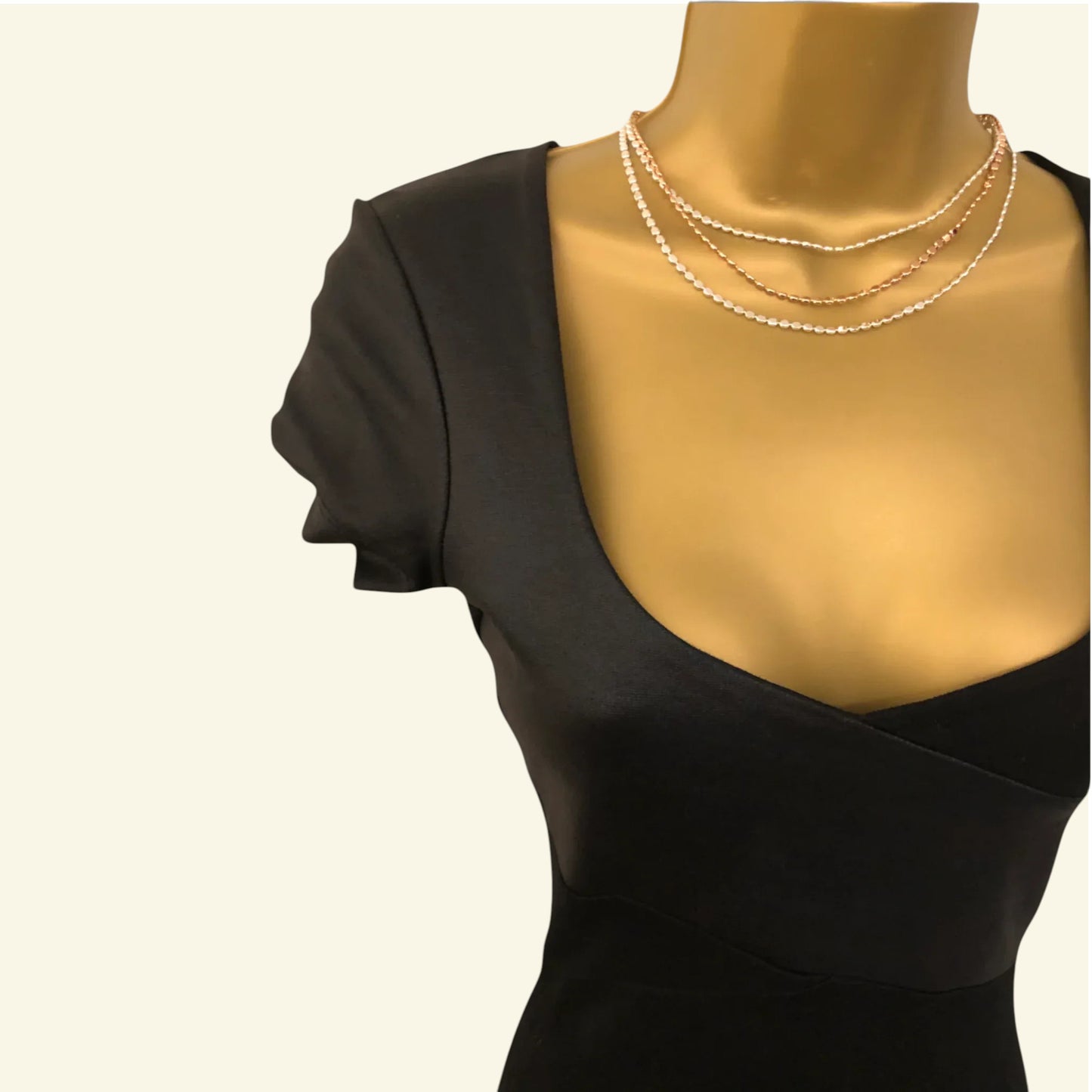 Mannequin wearing a black dress with a pearl necklace on a white background