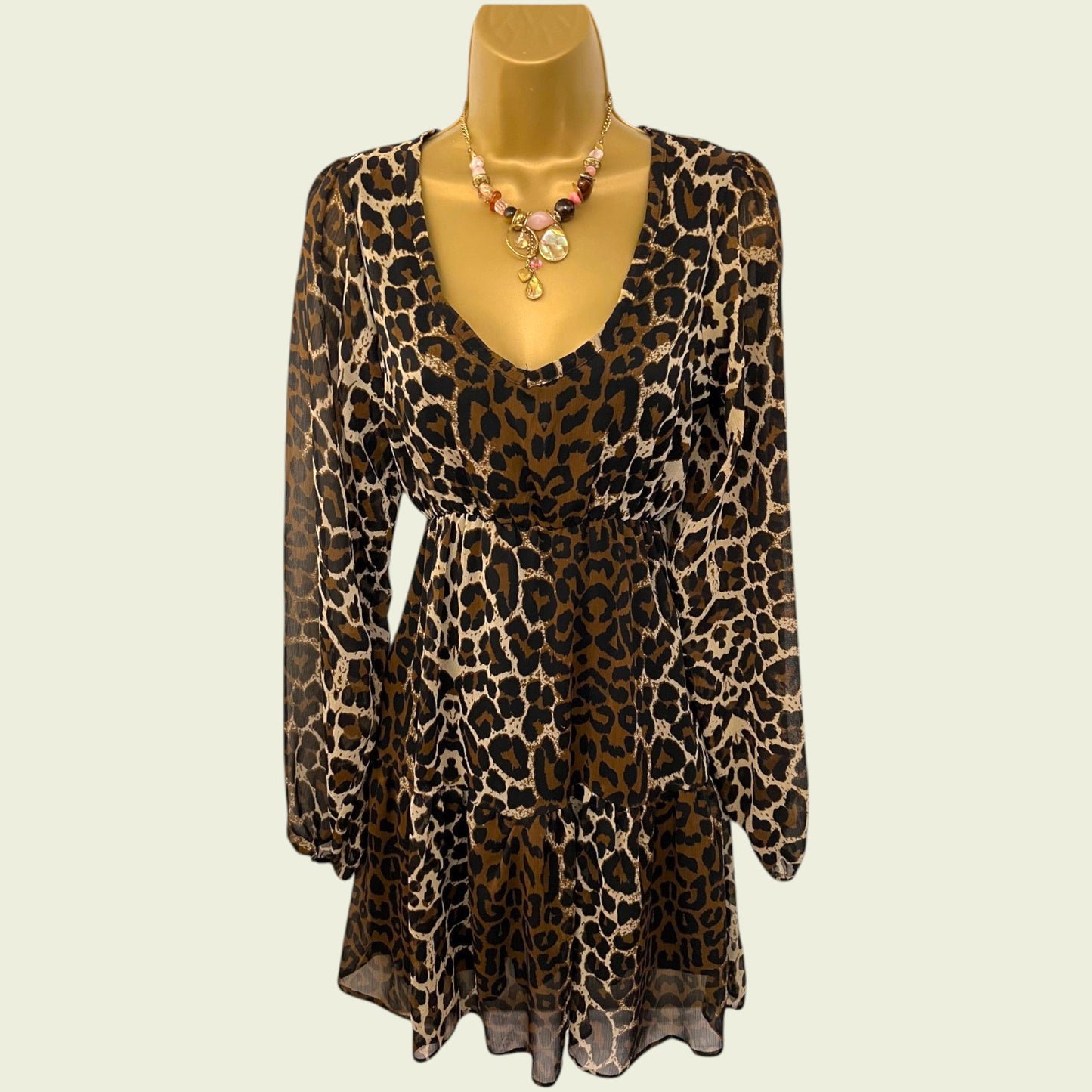 Mannequin wearing animal print chiffon dress on beige background