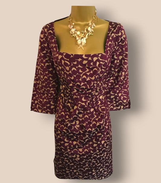 Purple patterned dress on a mannequin with a gold necklace against a beige background