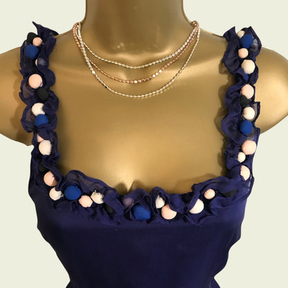 Navy dress with colorful pom-pom details on a mannequin against a plain background