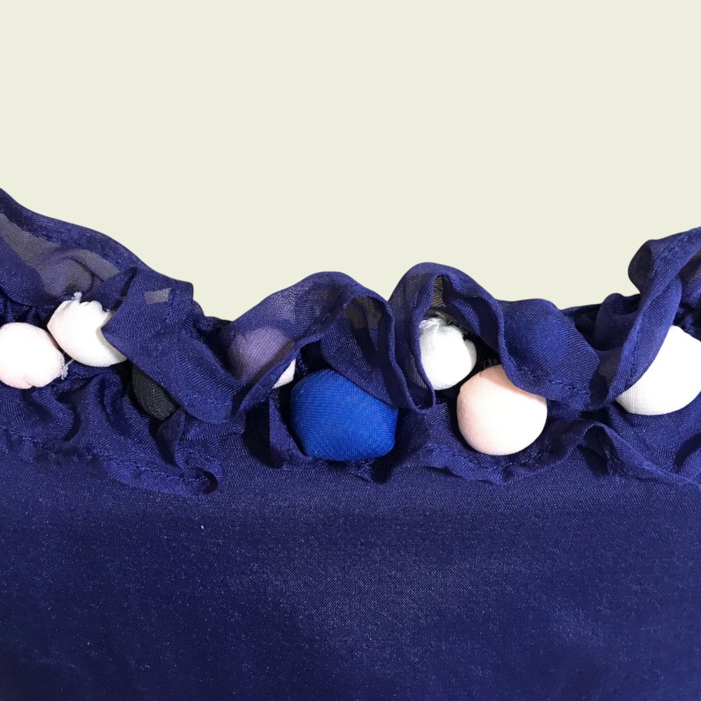 Navy blue fabric with white and blue buttons on a beige background
