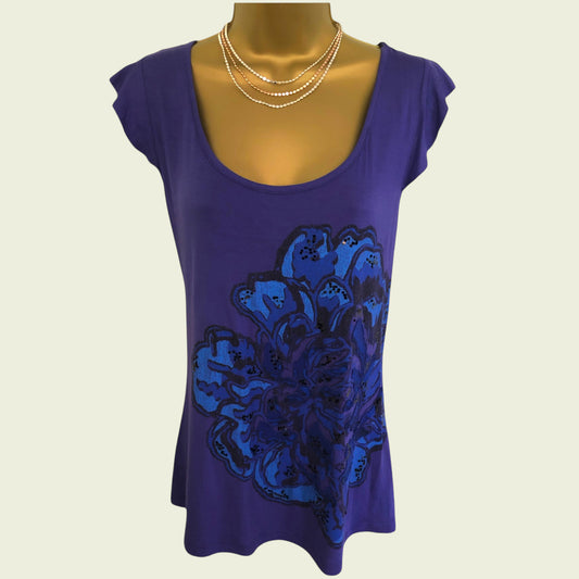 Purple top with blue floral design on a mannequin against a beige background