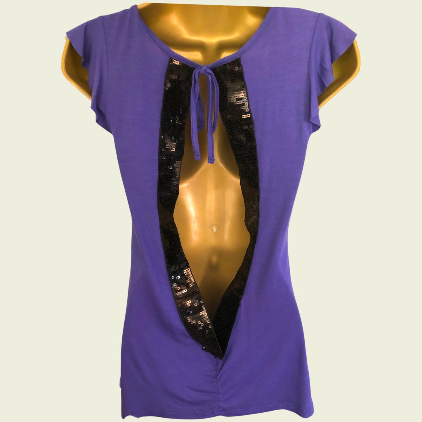 Purple top with black sequin details on a mannequin against a beige background