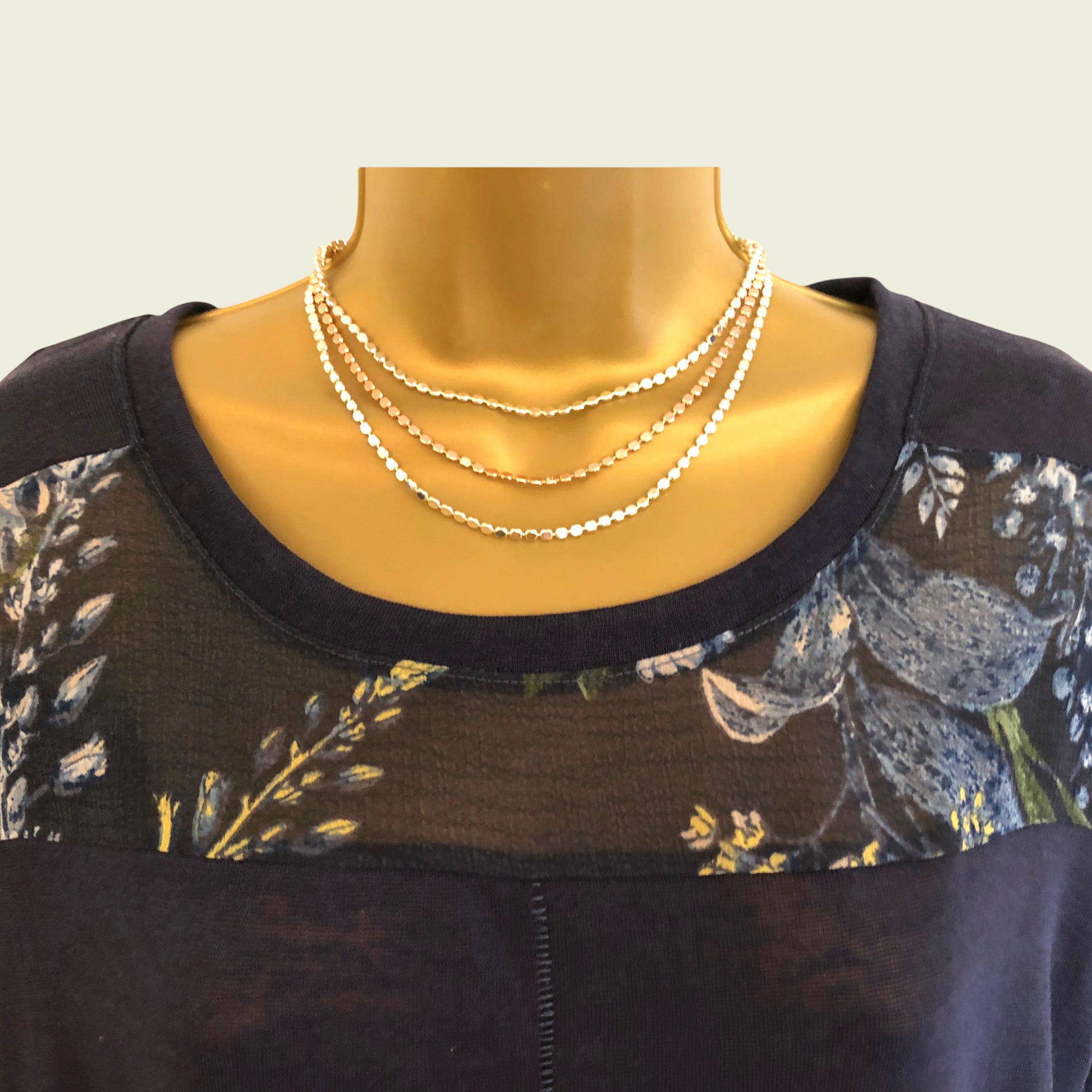 Mannequin wearing a dark floral dress with a necklace on a light background