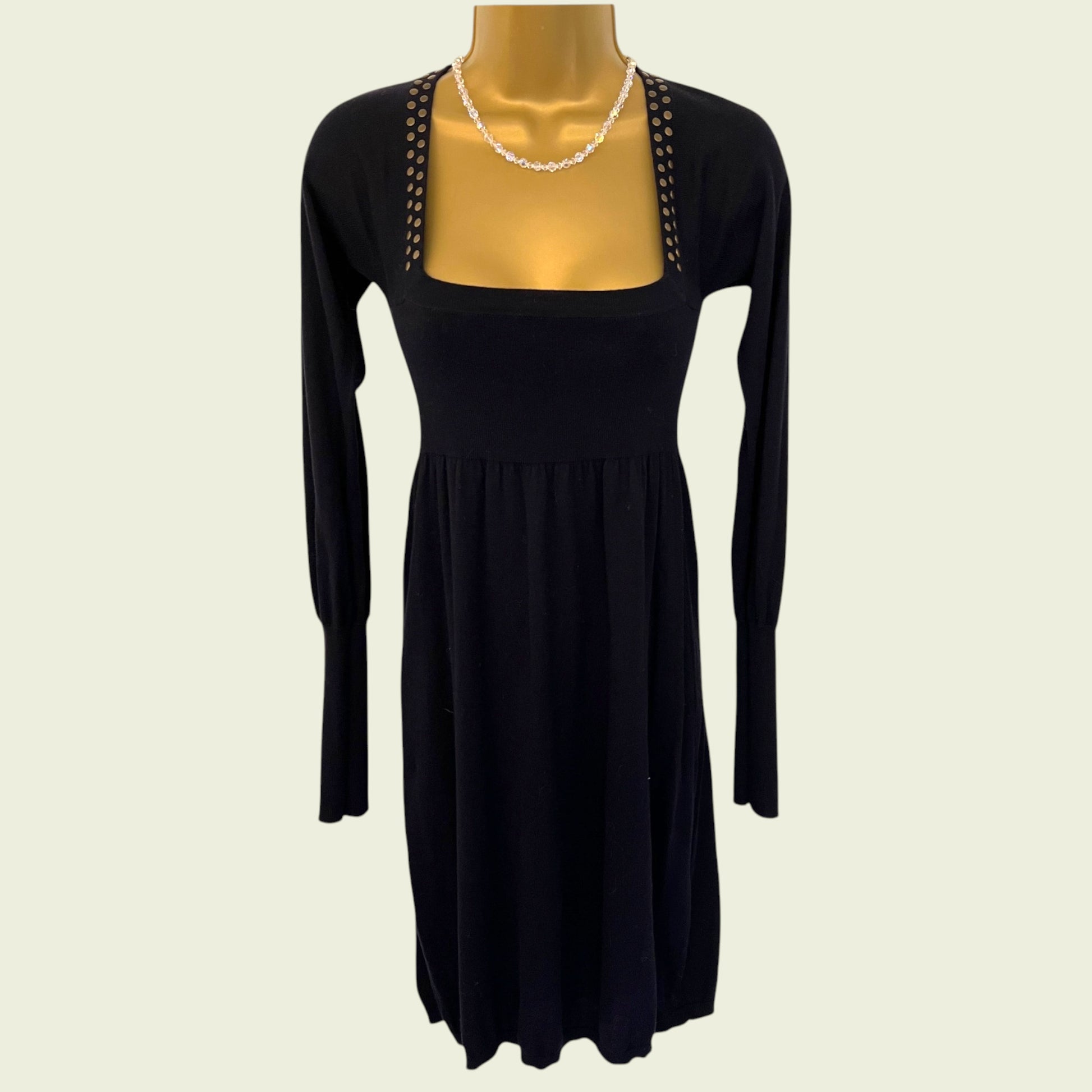 Black dress with long sleeves on a mannequin against a beige background