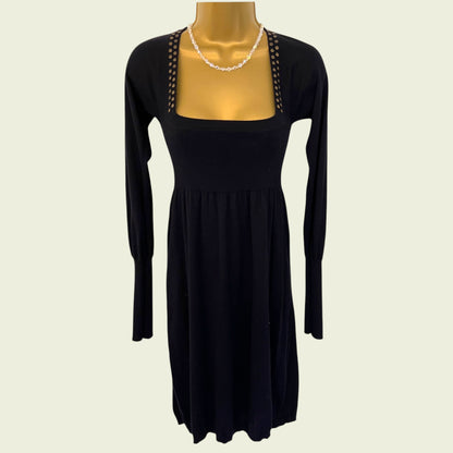 Black dress with long sleeves on a mannequin against a beige background