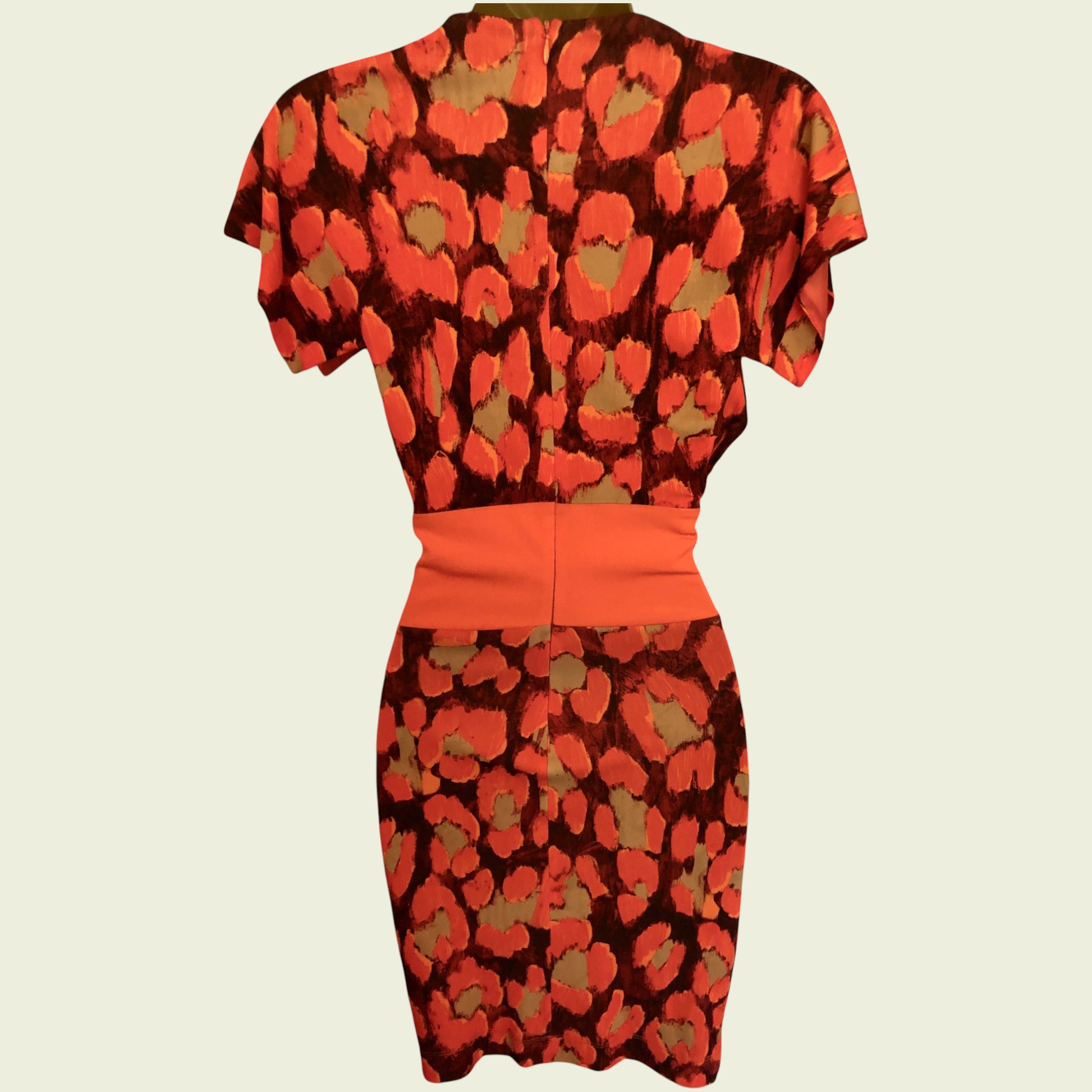 Model wearing bright orange and black dress on beige background