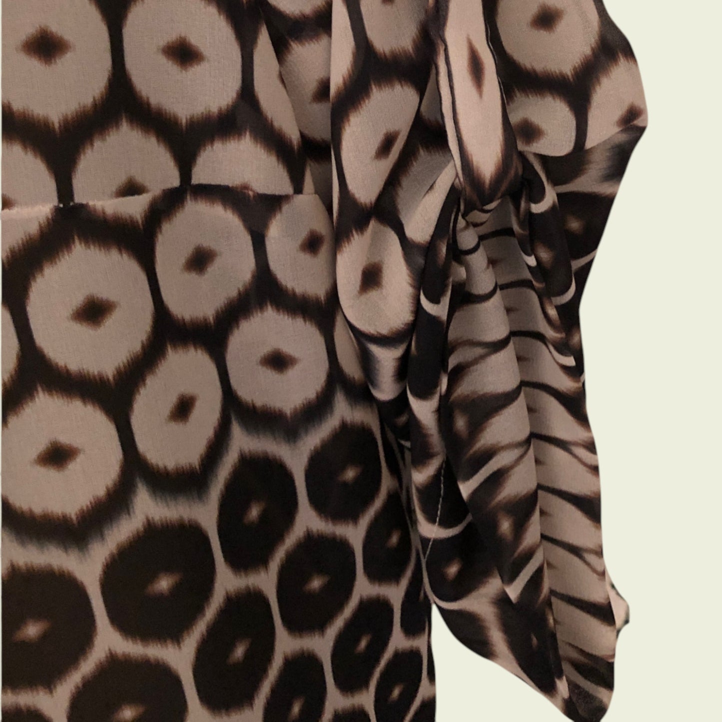 Close-up of fabric with a pattern of circular shapes in brown and beige on a beige background