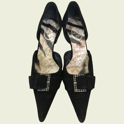 Black suede shoes with diamante buckle on beige background