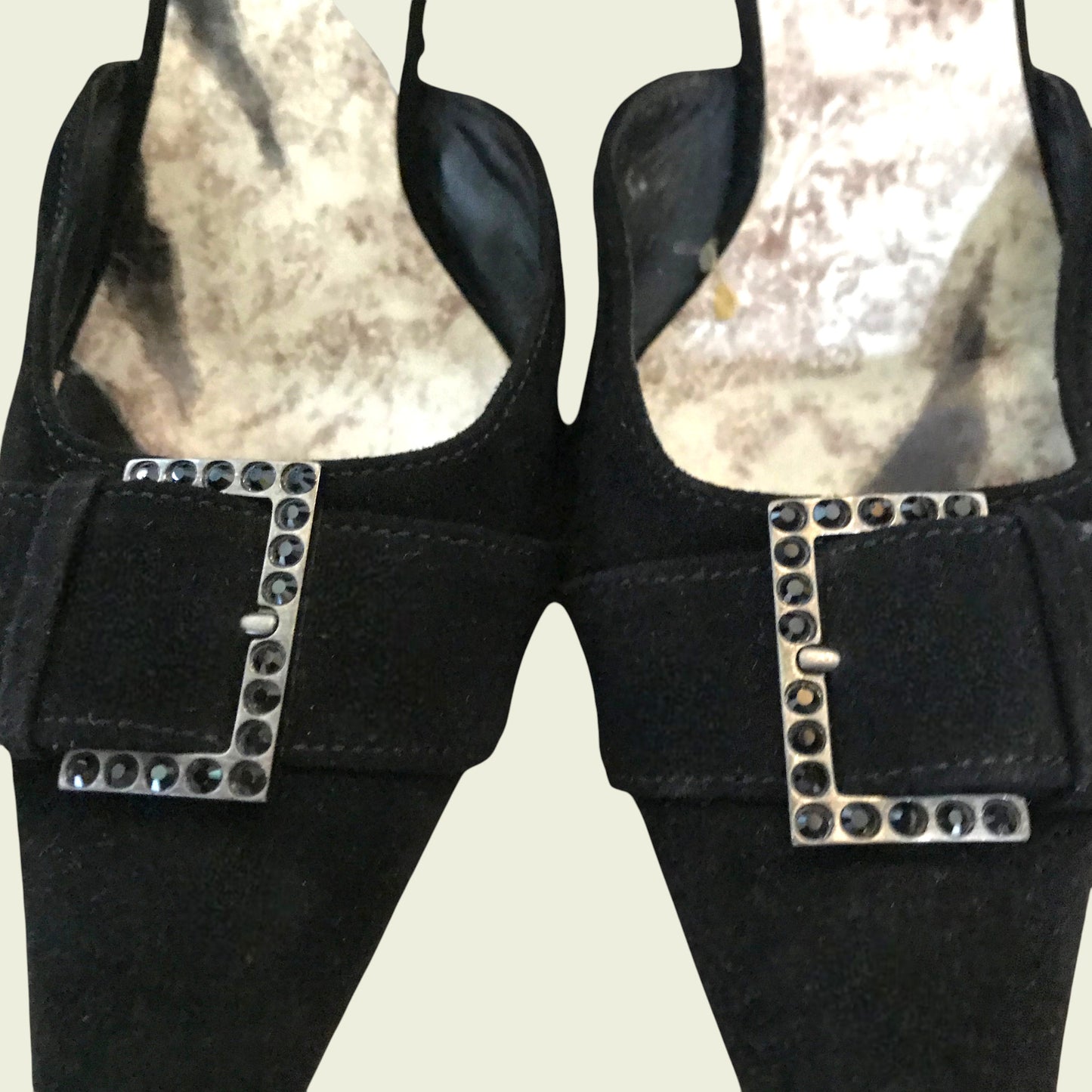 Black suede shoes with diamante buckle on beige background