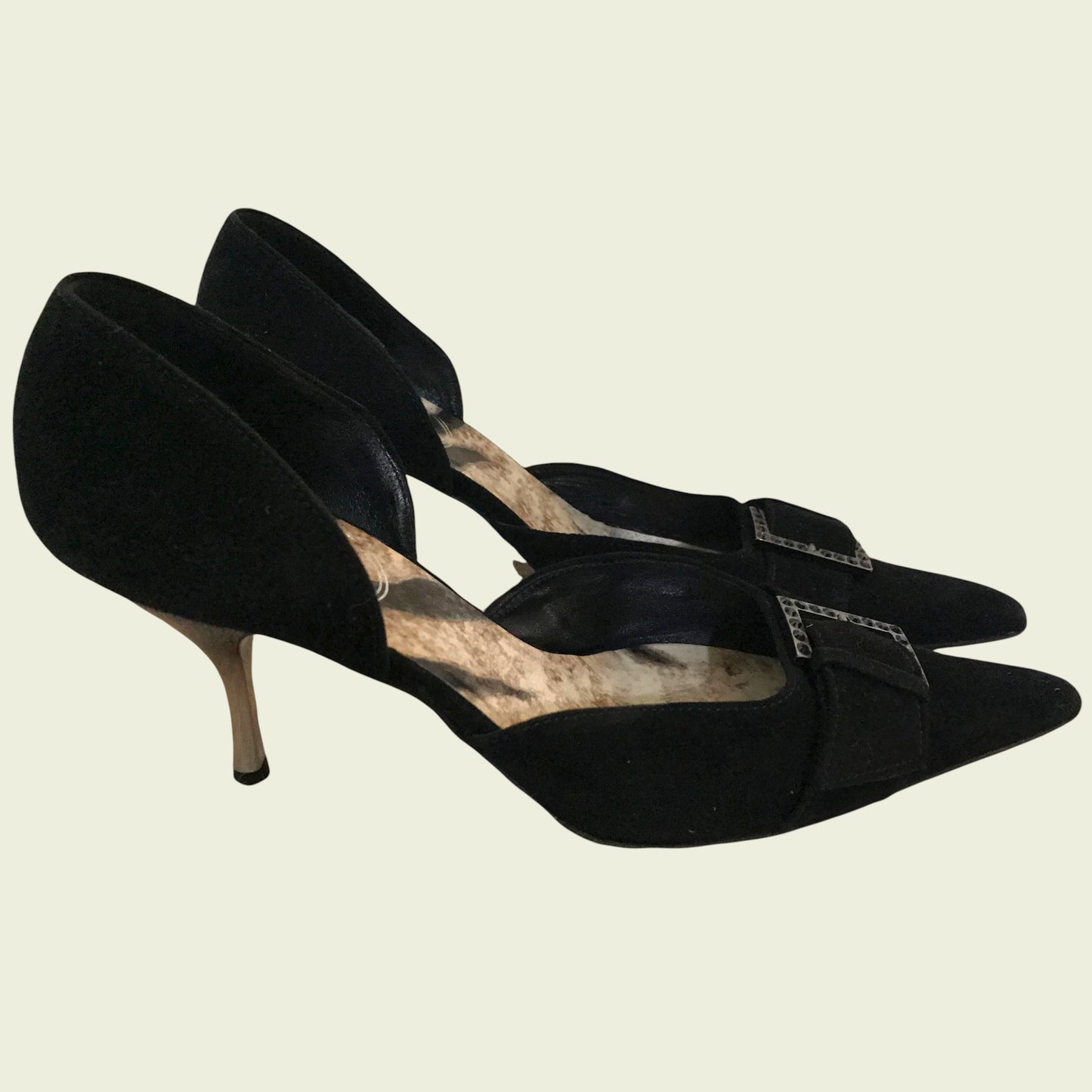 Black suede shoes with diamante buckle on beige background