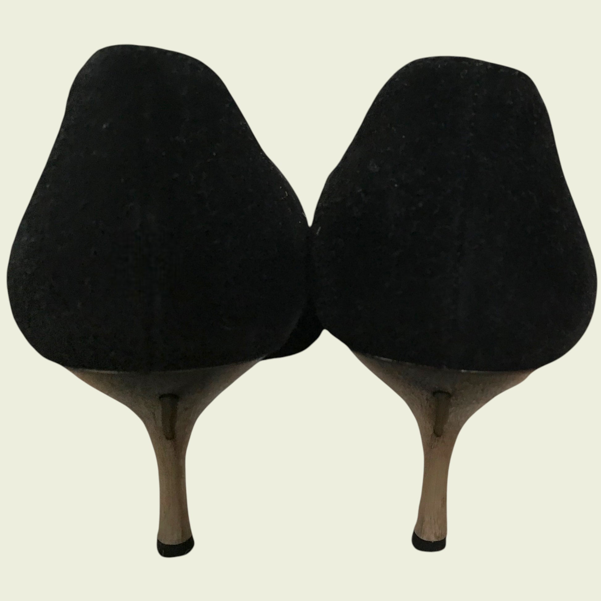 Back of black suede shoes showing heel on beige background