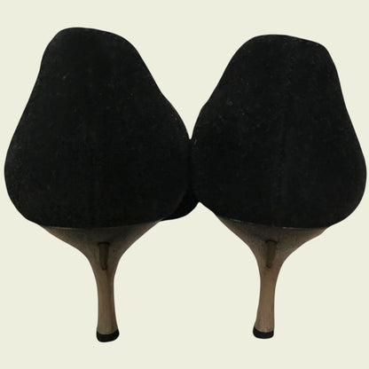 Back of black suede shoes showing heel on beige background